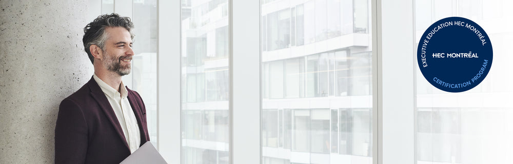 Personne dans un espace de bureaux moderne devant une baie vitrée, avec le sceau HEC Montréal en anglais visible.
